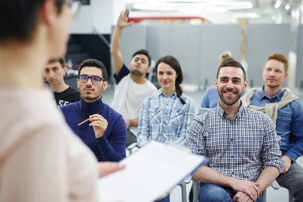 Um time de vendedores bem capacitados impulsiona as vendas no Natal Pessoas de frente sentadas olhando a professora