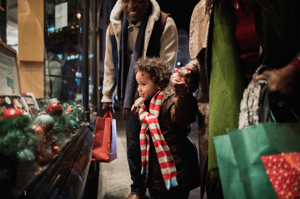 Decorar sua vitrine para o Natal atrai a atenção do público Menino vendo uma vitrine decorada para o Natal