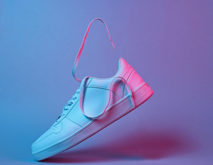 Tênis branco em fundo iluminado por luzes azul e rosa