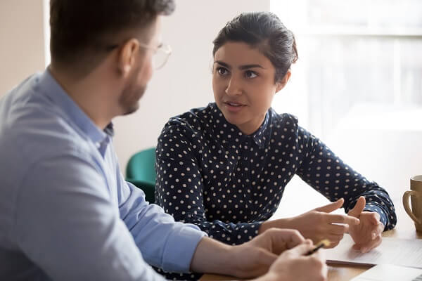 Entenda as necessidades do seu cliente Moça conversando com um homem em uma mesa