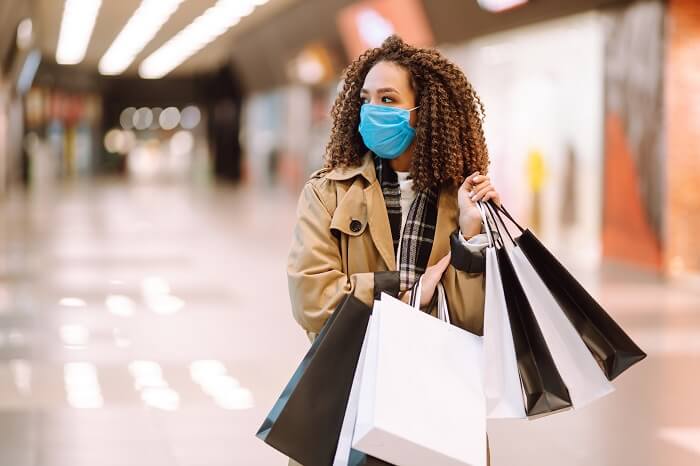 Mulher negra de máscara e securando sacola de compras