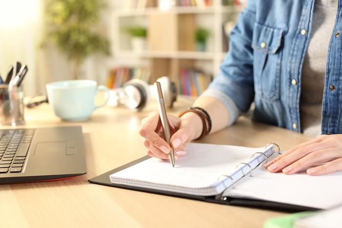 Mãos fazendo anotações em caderno