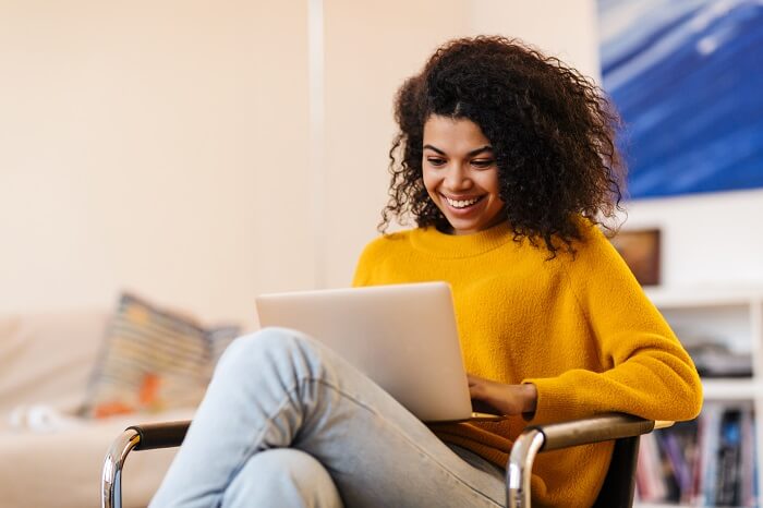 Mulher negra sentada com notebook nas pernas